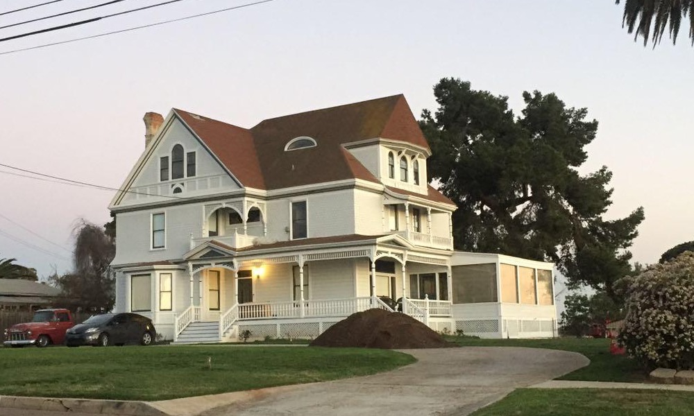 A large white Victorian house at dusk with a palm tree, the kind that sits on the market for months