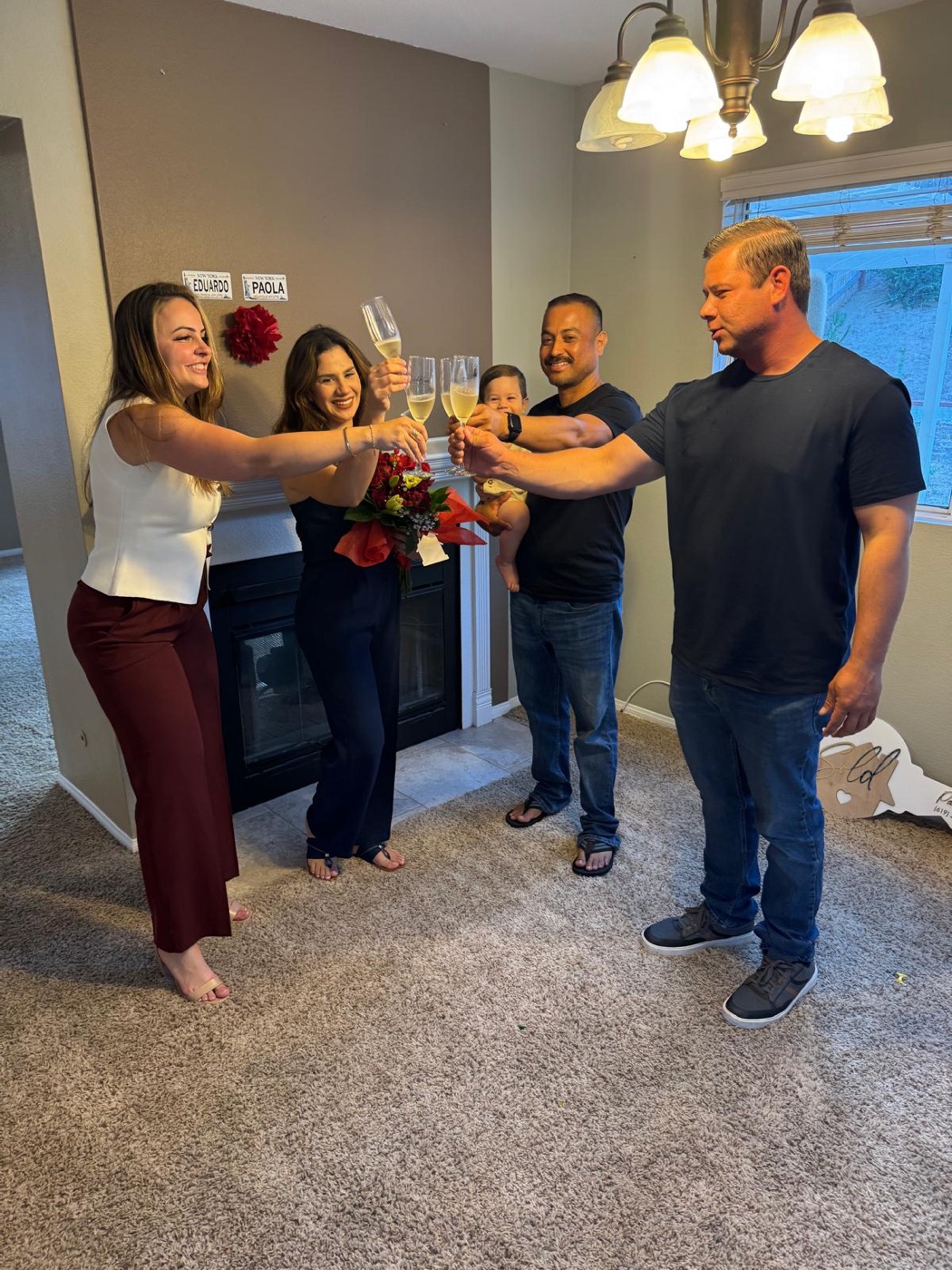 Paula and clients raising glasses in an empty living room