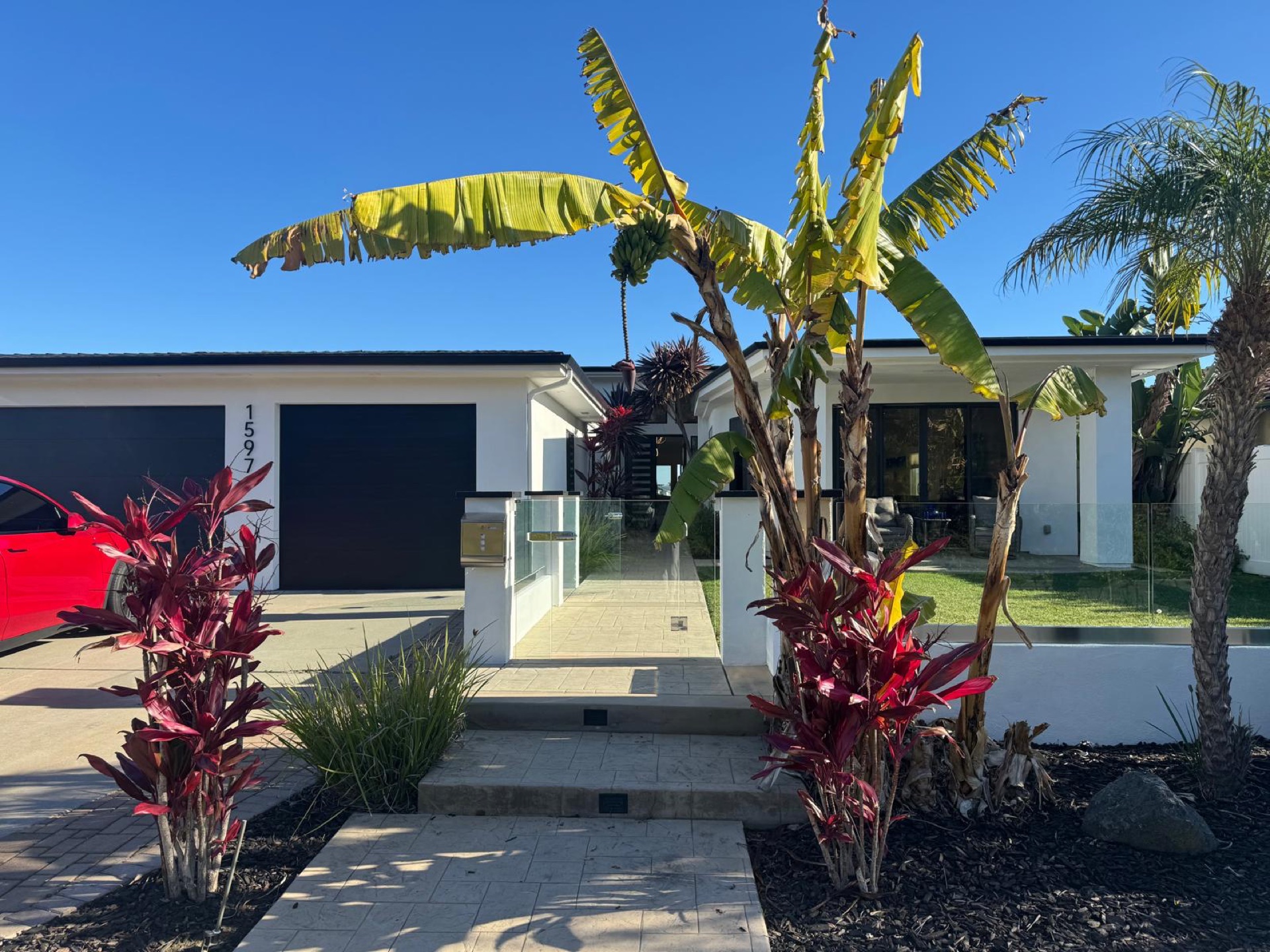 A modern white house with a glass-fronted entry under a deep blue sky