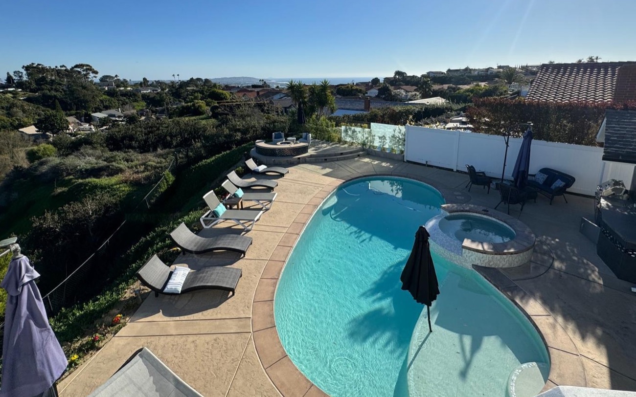 A backyard pool with a view of the hills and the ocean